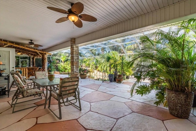 view of patio / terrace featuring ceiling fan, exterior bar, and glass enclosure