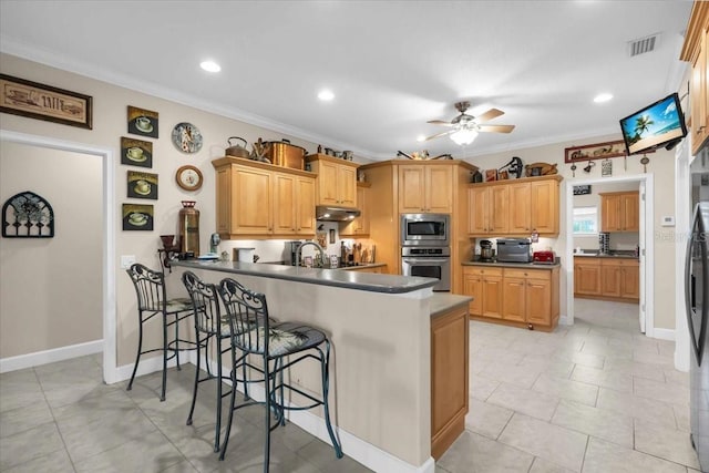 kitchen with a breakfast bar, ceiling fan, ornamental molding, kitchen peninsula, and stainless steel appliances