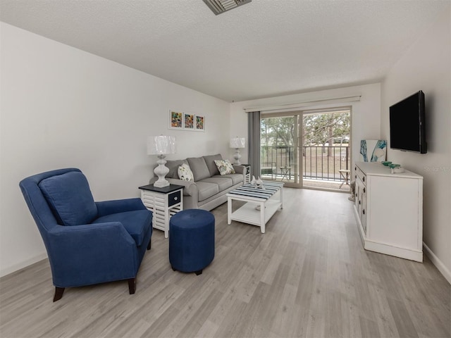 living room featuring a textured ceiling and light hardwood / wood-style flooring