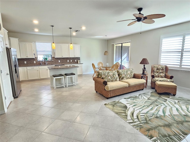 tiled living room featuring ceiling fan and sink