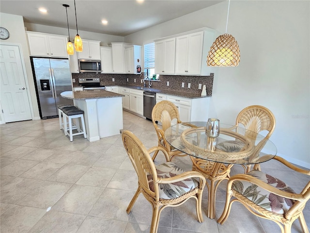 kitchen featuring a kitchen island, decorative light fixtures, white cabinetry, and appliances with stainless steel finishes