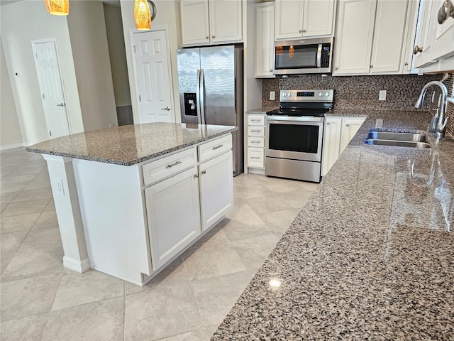 kitchen featuring tasteful backsplash, white cabinetry, stone counters, appliances with stainless steel finishes, and sink