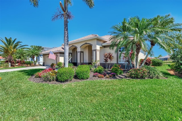 mediterranean / spanish-style home featuring a garage and a front lawn