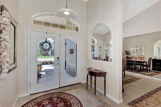 entrance foyer with light tile patterned floors, high vaulted ceiling, and french doors