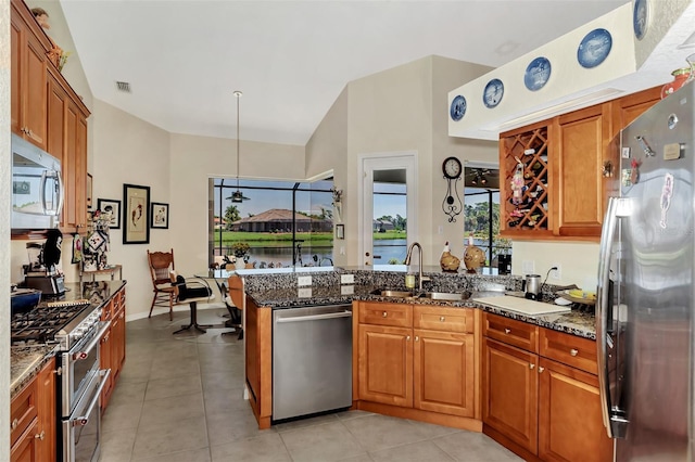 kitchen with dark stone countertops, sink, light tile patterned floors, and stainless steel appliances