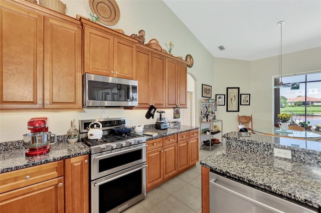 kitchen with dark stone countertops, lofted ceiling, and appliances with stainless steel finishes