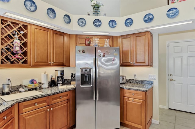 kitchen featuring stainless steel fridge with ice dispenser, light tile patterned floors, and stone countertops