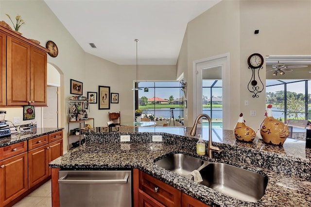 kitchen featuring vaulted ceiling, sink, dark stone countertops, dishwasher, and light tile patterned flooring