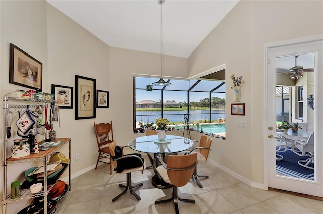 dining area featuring light tile patterned floors, a water view, vaulted ceiling, and ceiling fan