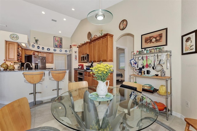 dining area featuring sink, light tile patterned floors, and high vaulted ceiling