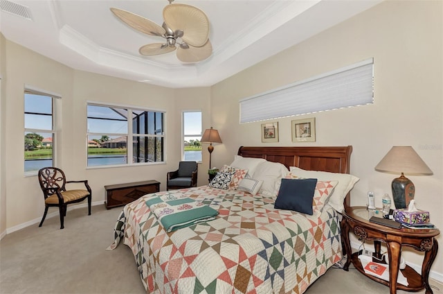 carpeted bedroom with ceiling fan, a raised ceiling, crown molding, and multiple windows