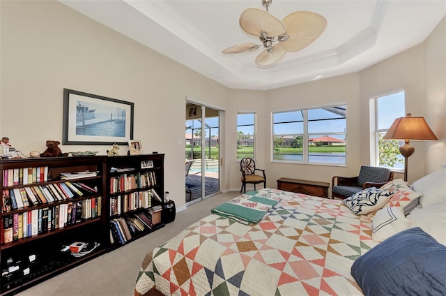 bedroom with carpet flooring, access to outside, a raised ceiling, and ceiling fan