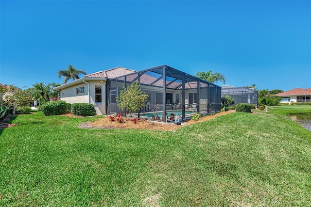 rear view of house featuring a lawn and glass enclosure