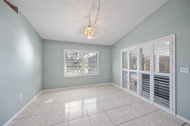 empty room featuring a chandelier, light tile patterned floors, a textured ceiling, and lofted ceiling