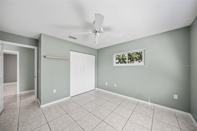 unfurnished bedroom featuring ceiling fan, a closet, light tile patterned floors, and a textured ceiling