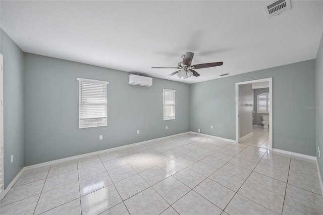 unfurnished room featuring ceiling fan, light tile patterned flooring, and an AC wall unit