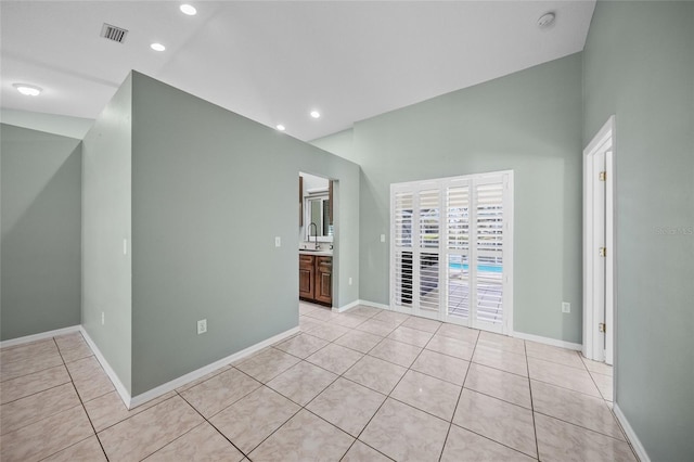 tiled spare room featuring sink and high vaulted ceiling