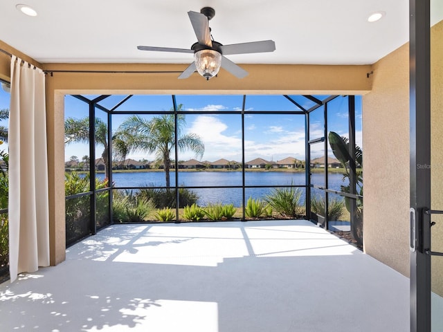 unfurnished sunroom featuring a water view and ceiling fan