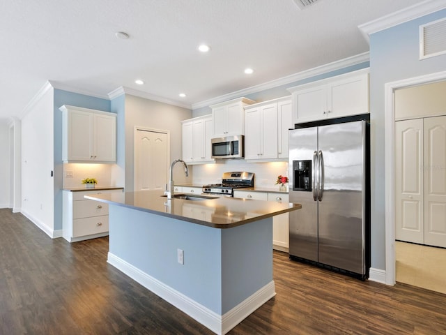 kitchen with crown molding, appliances with stainless steel finishes, backsplash, white cabinets, and a kitchen island with sink