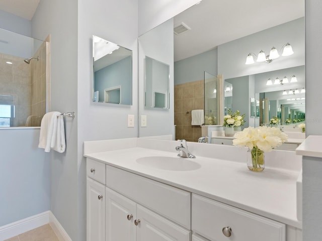 bathroom with a tile shower, tile patterned flooring, and vanity