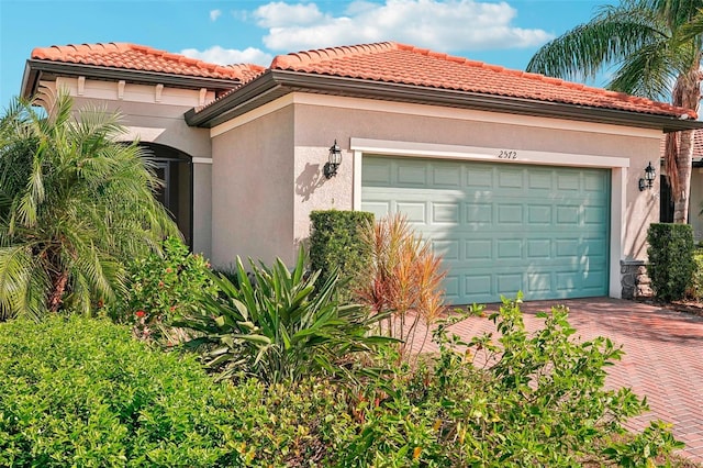 2572 Daisy Dr, North Port, FL 34289 - view of front of house featuring a garage, stucco siding, decorative driveway, and a tile roof