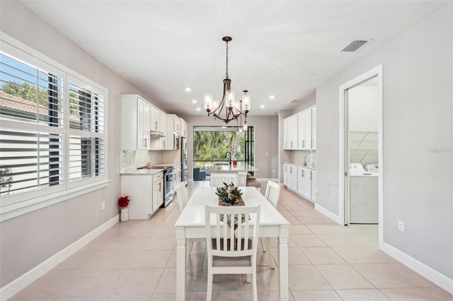 dining space featuring light tile patterned floors, an inviting chandelier, and washing machine and clothes dryer