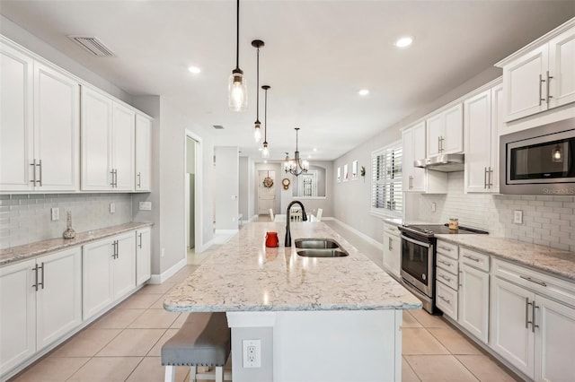 kitchen with appliances with stainless steel finishes, sink, a center island with sink, decorative light fixtures, and white cabinets