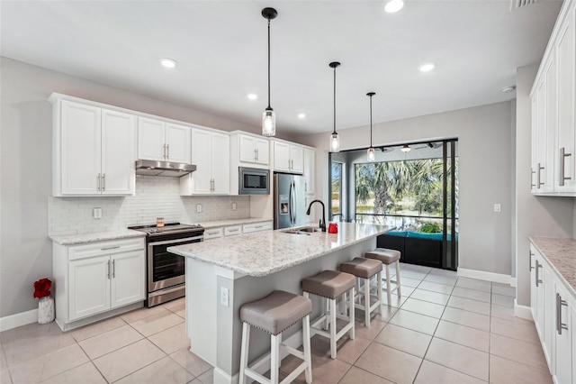 2572 Daisy Dr, North Port, FL 34289 - kitchen with stainless steel appliances, under cabinet range hood, tasteful backsplash, white cabinetry, and recessed lighting