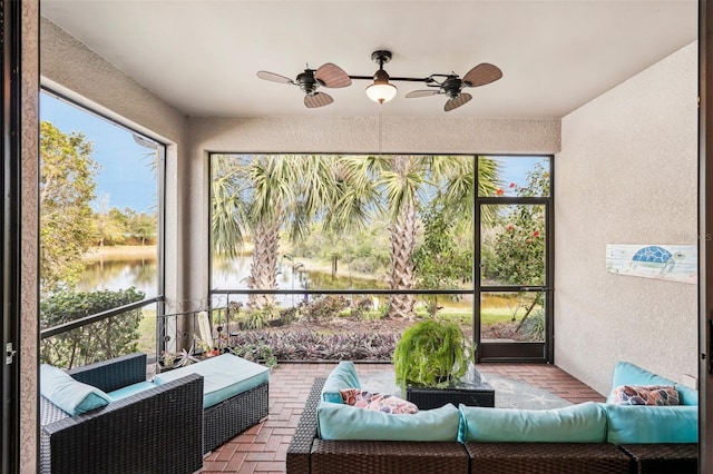 sunroom with a wealth of natural light, a water view, and ceiling fan