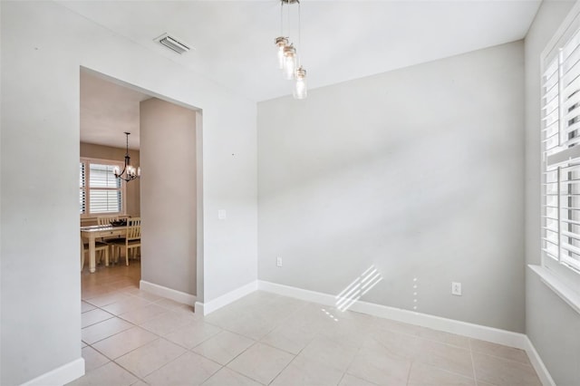 tiled empty room featuring an inviting chandelier