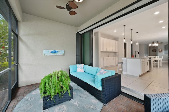 sunroom / solarium featuring sink and ceiling fan with notable chandelier