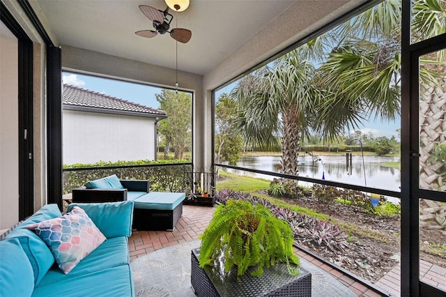 sunroom with ceiling fan and a water view