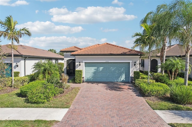 2572 Daisy Dr, North Port, FL 34289 - mediterranean / spanish-style home featuring an attached garage, decorative driveway, a tiled roof, and stucco siding