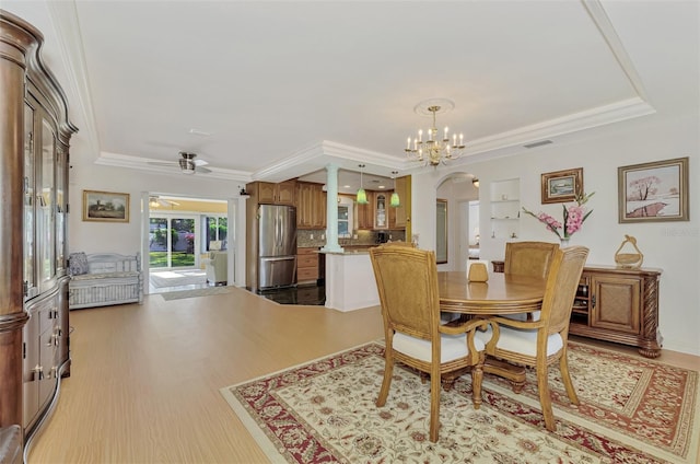 dining space featuring ceiling fan with notable chandelier, light wood-type flooring, crown molding, and a tray ceiling