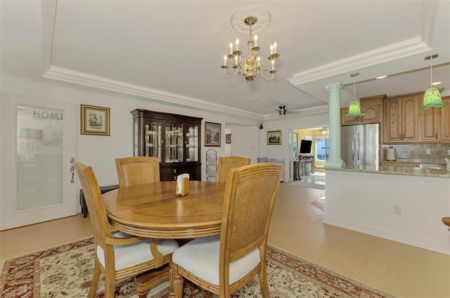 dining area featuring ornamental molding, light hardwood / wood-style flooring, a tray ceiling, and a chandelier