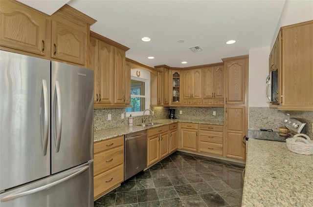 kitchen featuring tasteful backsplash, light stone counters, sink, and appliances with stainless steel finishes