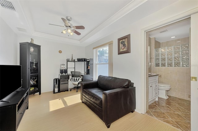 tiled living room with a tray ceiling, ceiling fan, and tile walls