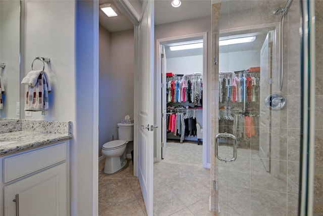 bathroom with toilet, vanity, and a shower with shower door