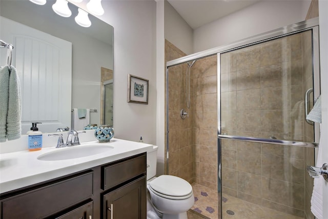 bathroom with a shower with shower door, toilet, and vanity