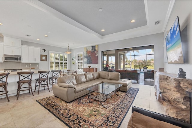 living room featuring ornamental molding, light tile patterned floors, and a tray ceiling