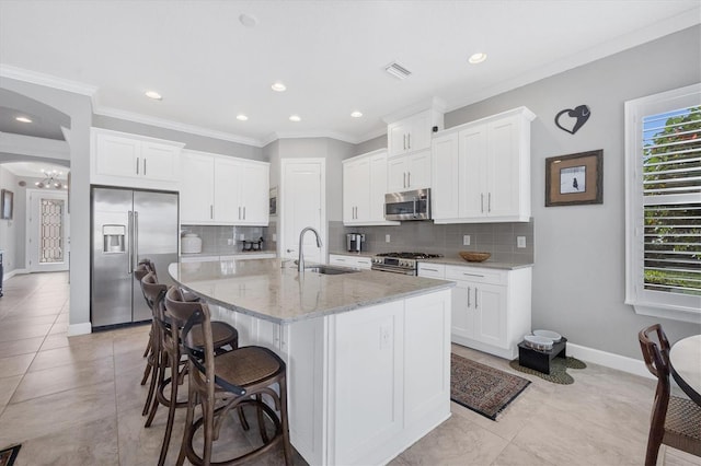 kitchen with white cabinets, sink, an island with sink, appliances with stainless steel finishes, and tasteful backsplash