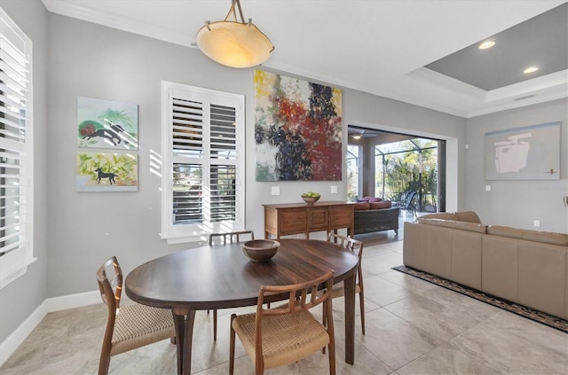 dining space with ornamental molding, light tile patterned floors, and a tray ceiling