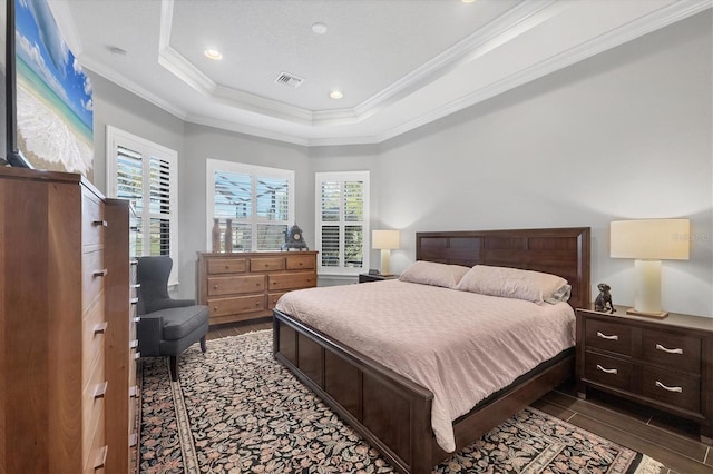 bedroom with wood finished floors, a tray ceiling, ornamental molding, visible vents, and recessed lighting