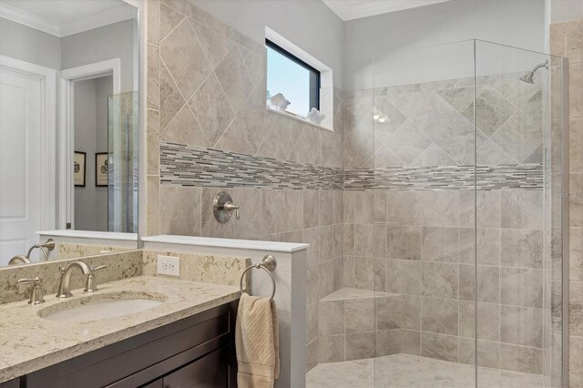 bathroom with a tile shower, crown molding, and vanity
