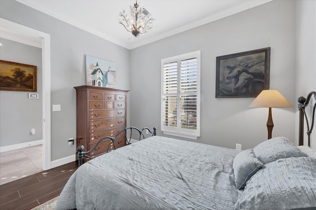 bedroom featuring a notable chandelier, baseboards, crown molding, and wood finished floors