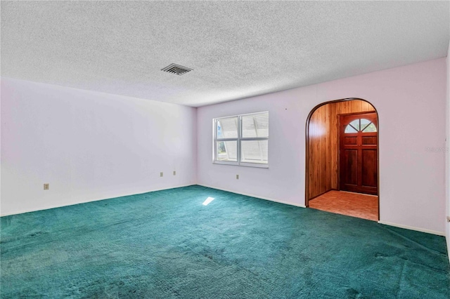 carpeted empty room featuring a textured ceiling