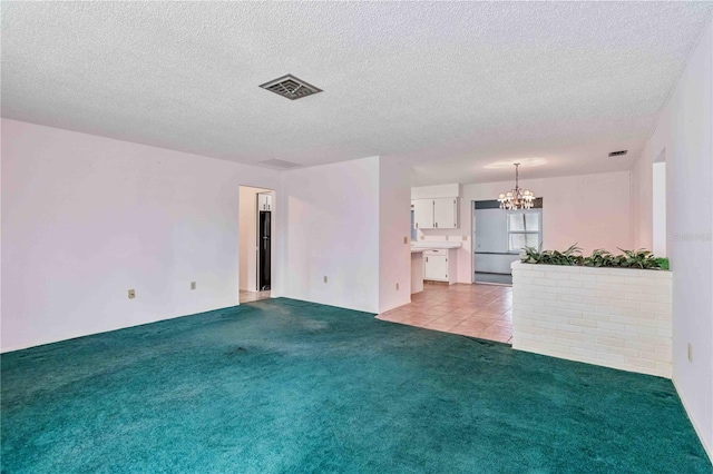 unfurnished living room with light colored carpet, a textured ceiling, and a notable chandelier