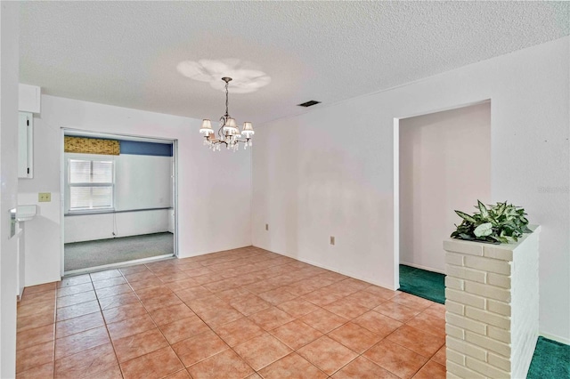 tiled empty room with a chandelier and a textured ceiling