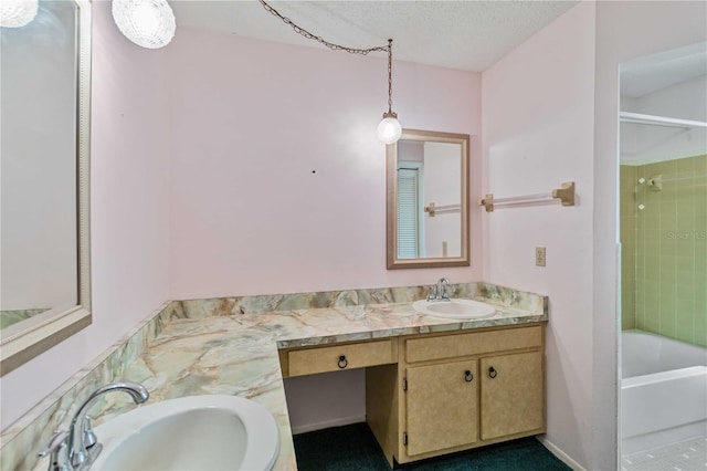 bathroom featuring a textured ceiling, vanity, and tiled shower / bath