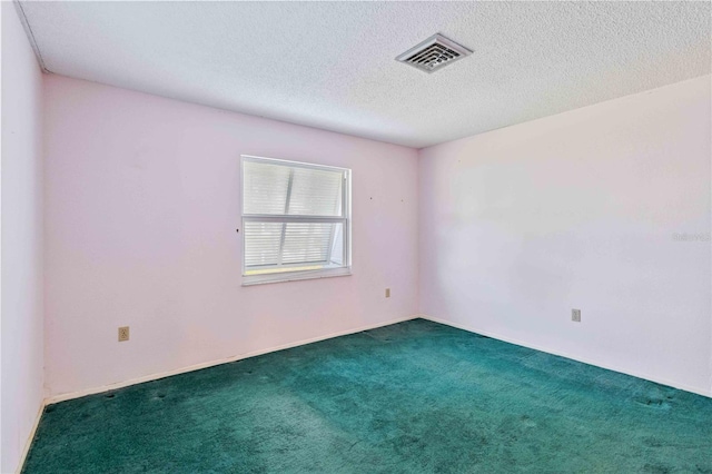 spare room featuring dark carpet and a textured ceiling